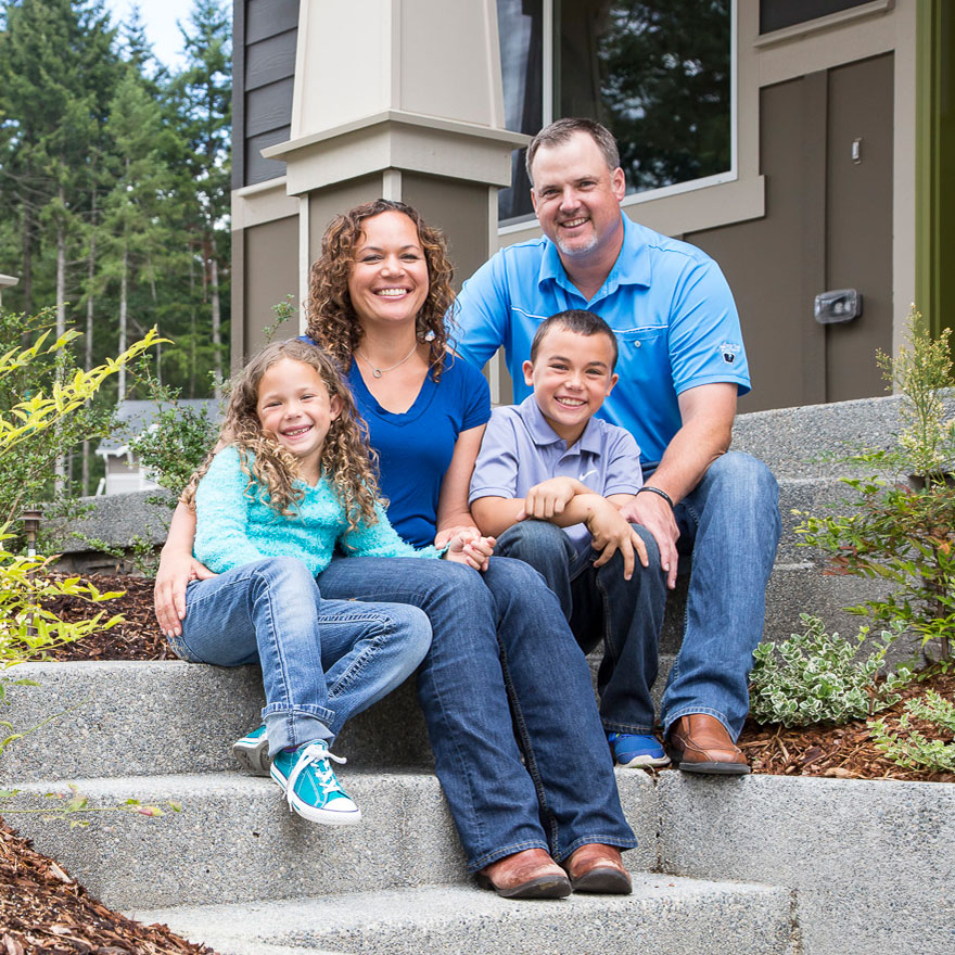 Image of family sitting on steps in front of new home at Harbor Hill